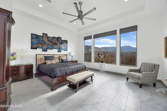 bedroom with a raised ceiling, ceiling fan, and a mountain view