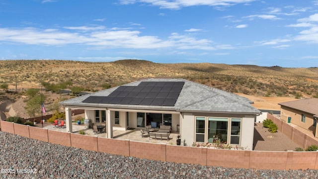 rear view of house with a mountain view, a patio area, and solar panels