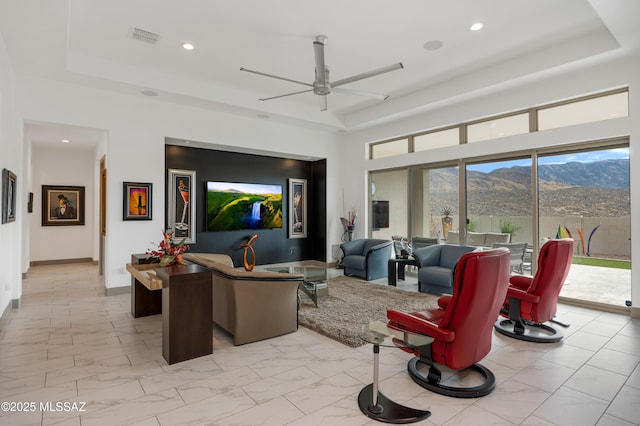 living room with a raised ceiling and ceiling fan