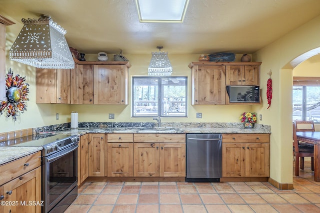 kitchen with light stone counters, stainless steel appliances, light tile patterned floors, and sink