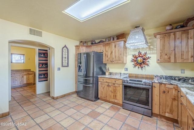 kitchen featuring appliances with stainless steel finishes, light stone countertops, and light tile patterned floors