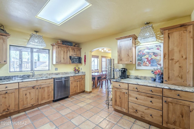 kitchen featuring light stone countertops, dishwasher, light tile patterned floors, and sink