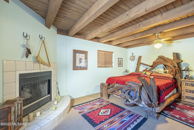 carpeted bedroom with a fireplace, ceiling fan, wood ceiling, and beam ceiling