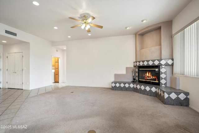 tiled living room featuring ceiling fan and a tiled fireplace