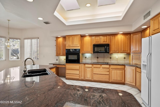 kitchen featuring black appliances, hanging light fixtures, sink, and a tray ceiling