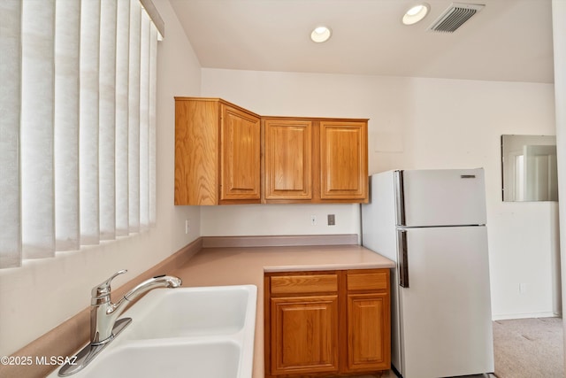 kitchen featuring sink, light carpet, and white fridge