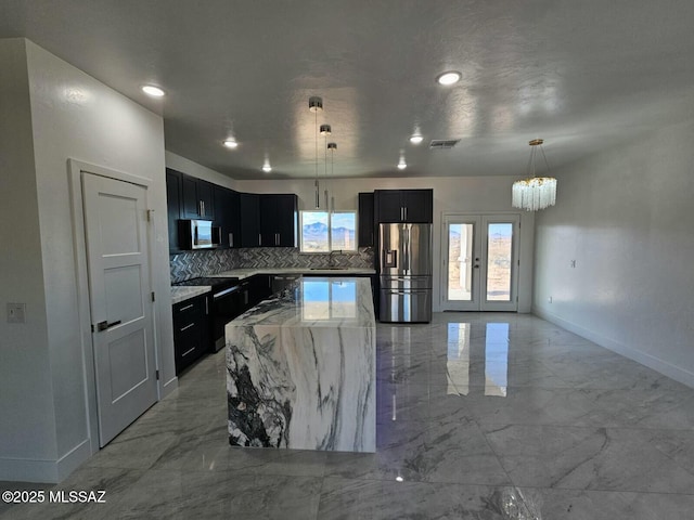 kitchen featuring marble finish floor, stainless steel appliances, visible vents, hanging light fixtures, and dark cabinets