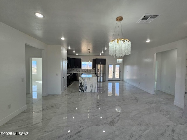 unfurnished living room with french doors, marble finish floor, an inviting chandelier, and visible vents