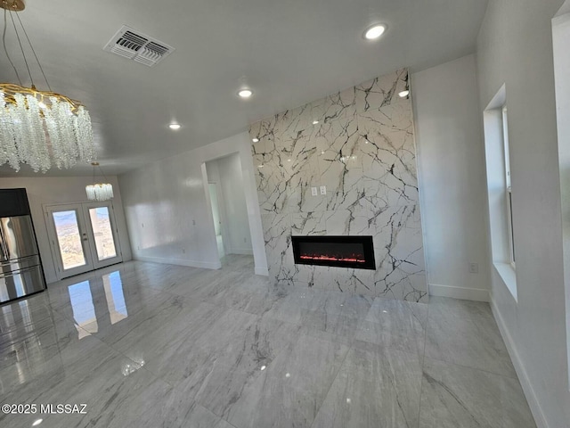 unfurnished living room featuring french doors, recessed lighting, visible vents, a high end fireplace, and baseboards