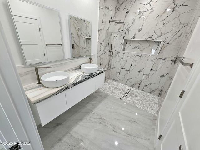 full bathroom featuring double vanity, marble finish floor, a marble finish shower, and a sink