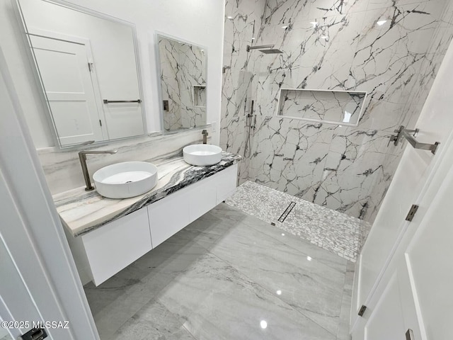 bathroom featuring a sink, a marble finish shower, marble finish floor, and double vanity