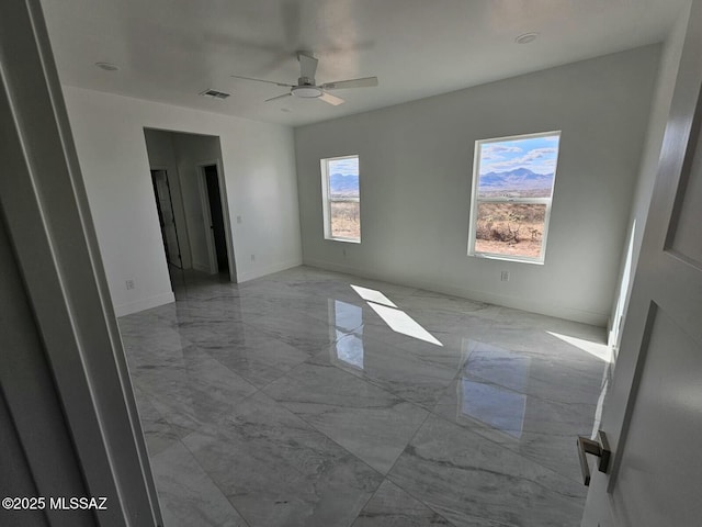 spare room with marble finish floor, baseboards, visible vents, and a ceiling fan