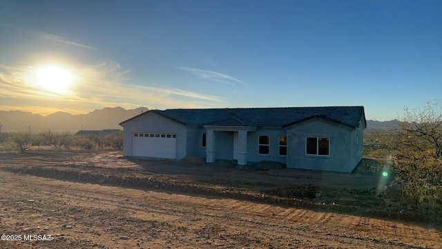 view of front of property featuring a garage, dirt driveway, and a mountain view