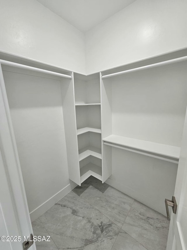 walk in closet featuring marble finish floor