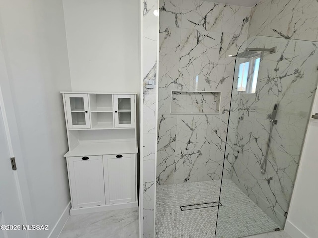 full bath featuring marble finish floor, a marble finish shower, and baseboards