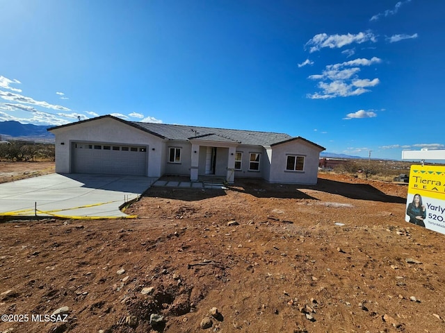 single story home with a garage, concrete driveway, and stucco siding