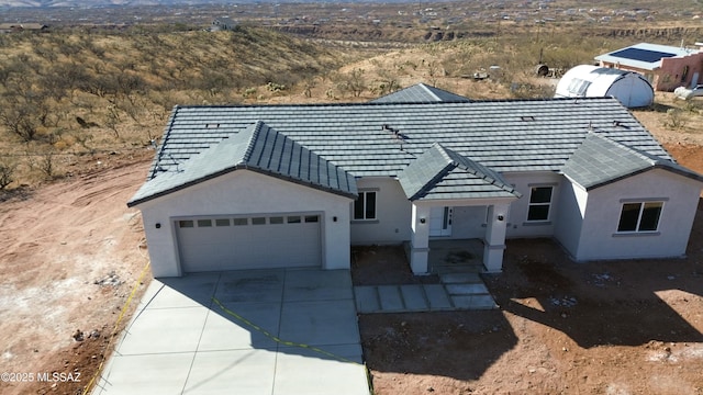 view of front of property featuring an attached garage, concrete driveway, and stucco siding