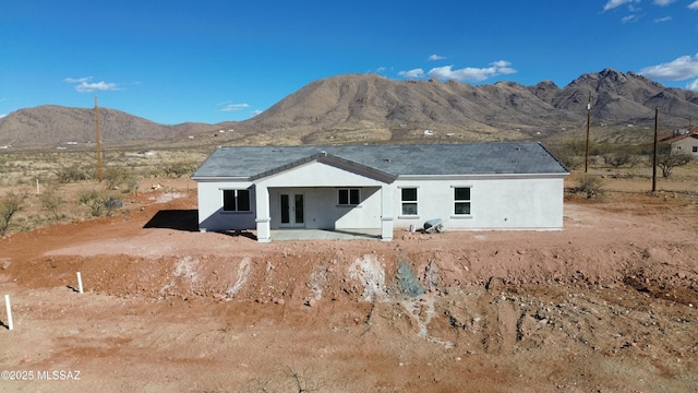 rear view of property with french doors, a mountain view, and stucco siding