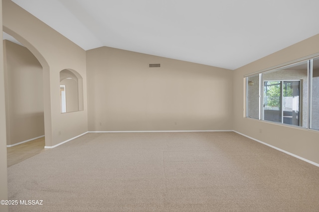 carpeted empty room with vaulted ceiling