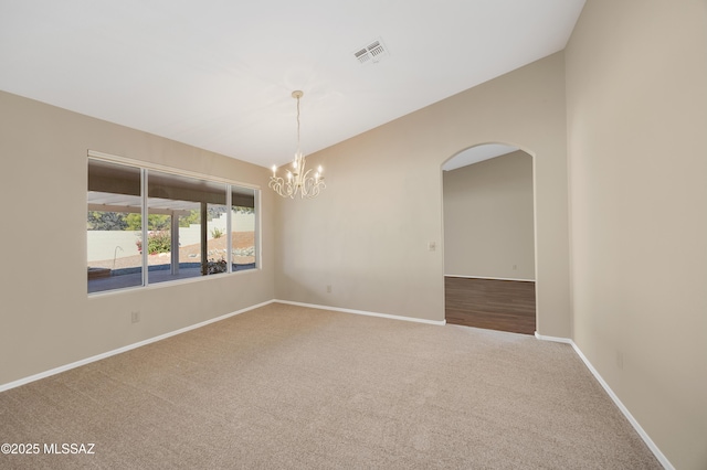 carpeted empty room featuring a chandelier