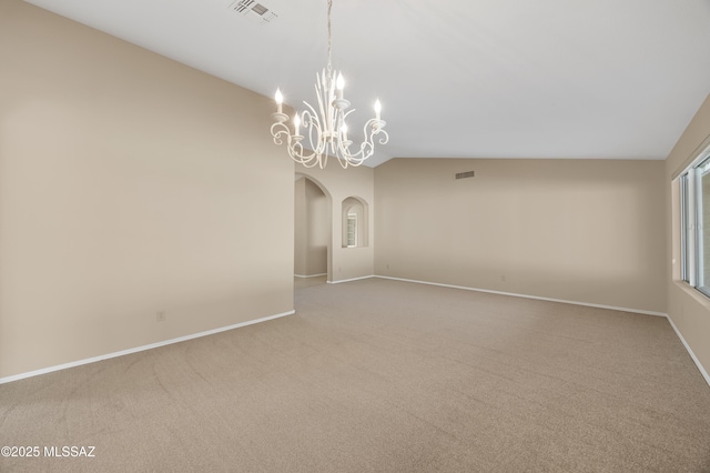 carpeted empty room with a chandelier and vaulted ceiling