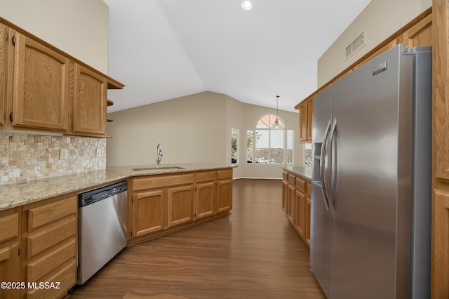 kitchen with kitchen peninsula, appliances with stainless steel finishes, backsplash, decorative light fixtures, and sink