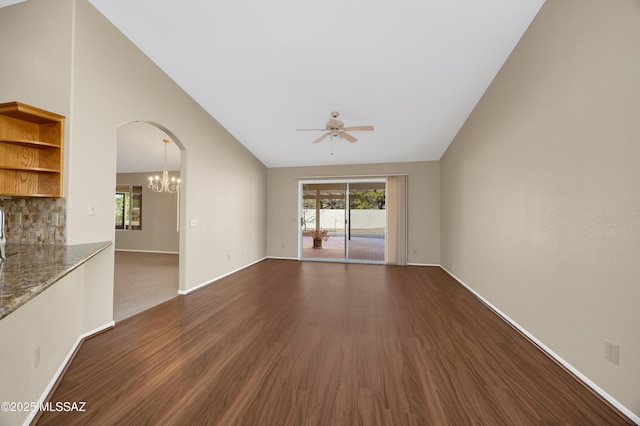 unfurnished living room with vaulted ceiling, dark wood-type flooring, and ceiling fan with notable chandelier