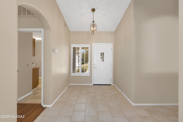 foyer entrance featuring light tile patterned floors and a notable chandelier