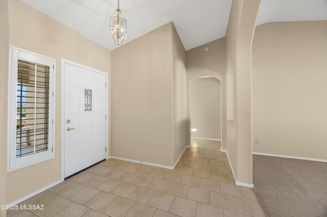 tiled foyer featuring vaulted ceiling and an inviting chandelier