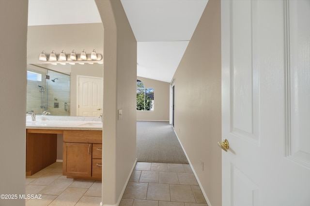 hall with sink, light tile patterned floors, and vaulted ceiling