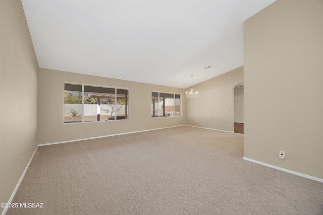 spare room with lofted ceiling, light carpet, and a notable chandelier