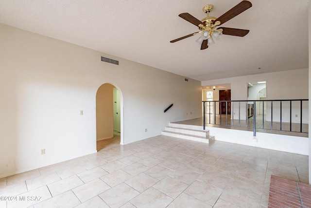 tiled empty room featuring ceiling fan and a textured ceiling