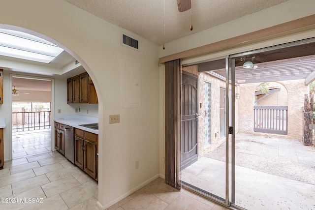 kitchen featuring stainless steel dishwasher, sink, light tile patterned floors, and a textured ceiling