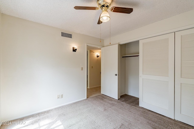 unfurnished bedroom with carpet flooring, a textured ceiling, a closet, and ceiling fan