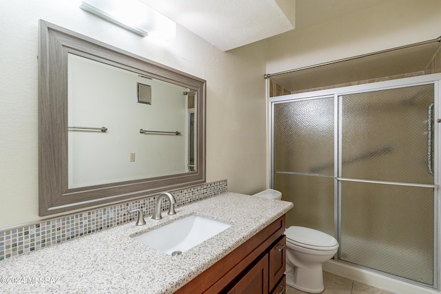 bathroom featuring decorative backsplash, vanity, an enclosed shower, and toilet