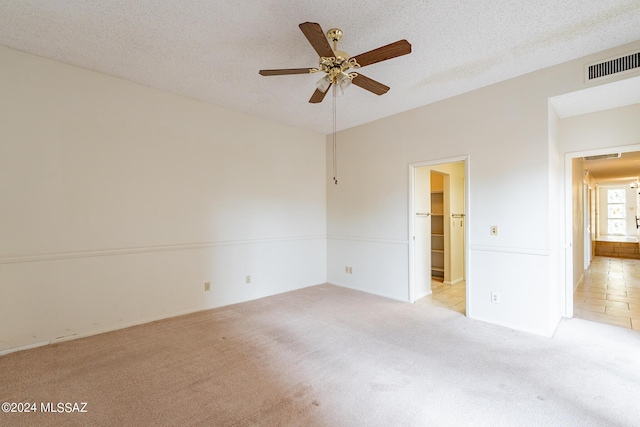 carpeted spare room with ceiling fan and a textured ceiling