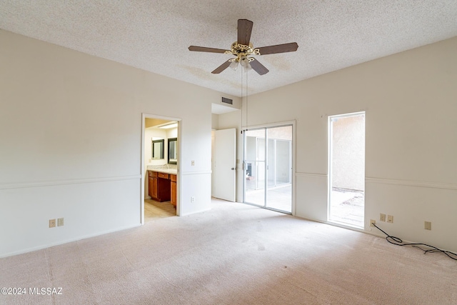 unfurnished bedroom featuring ensuite bathroom, ceiling fan, light carpet, and a textured ceiling