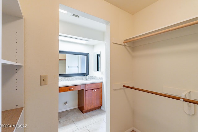 spacious closet featuring sink and light tile patterned floors