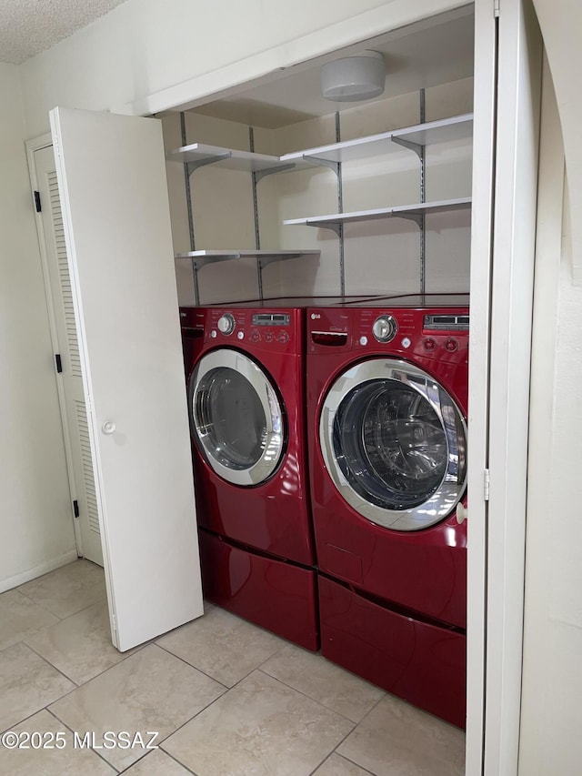 clothes washing area featuring washing machine and dryer, light tile patterned floors, and a textured ceiling