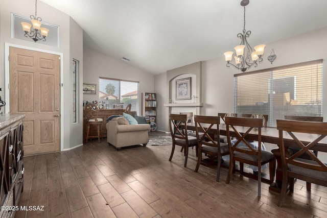 dining area with an inviting chandelier, vaulted ceiling, and dark hardwood / wood-style floors