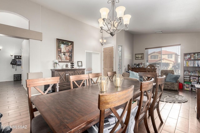 dining space featuring lofted ceiling, a notable chandelier, and light hardwood / wood-style floors