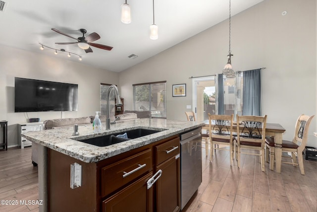 kitchen featuring stainless steel dishwasher, decorative light fixtures, sink, and a center island with sink