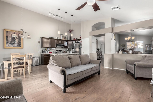 living room with high vaulted ceiling, dark hardwood / wood-style floors, and ceiling fan with notable chandelier