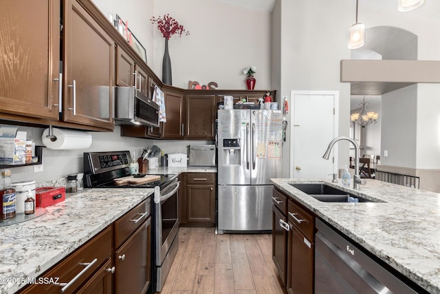 kitchen with sink, decorative light fixtures, a chandelier, stainless steel appliances, and light stone countertops