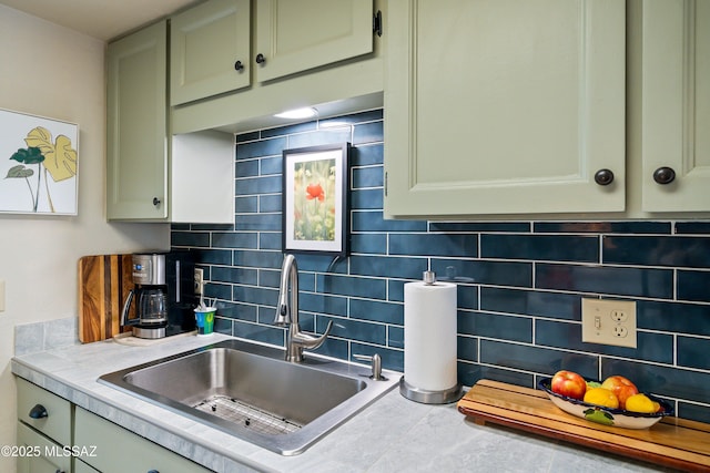 kitchen with backsplash, green cabinets, and sink