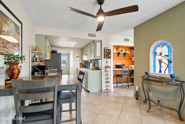 dining room with a ceiling fan, visible vents, a textured ceiling, and light tile patterned floors