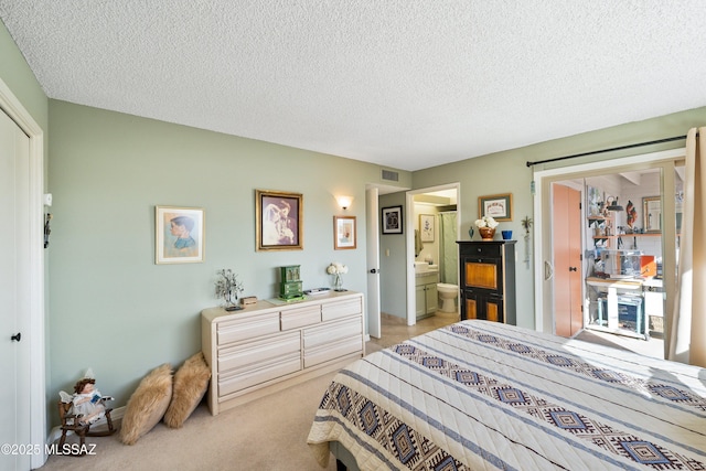 bedroom featuring light carpet, a closet, a textured ceiling, and ensuite bath