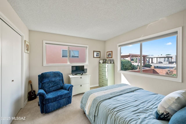 bedroom featuring light carpet, a closet, and a textured ceiling