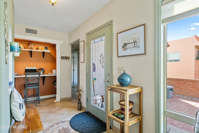 doorway with light tile patterned floors and a textured ceiling