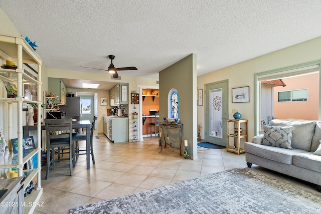 living room with ceiling fan, light tile patterned floors, and a textured ceiling